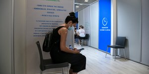 κοπέλα καάθεται σε καρέκλα σε εμβολιαστικό κέντρο