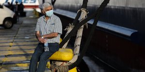 Ενας άνδρας μπροστά από πλοίο που μπαρκάρει για νησί
