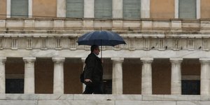 Άνδρας με ομπρέλα έξω από τη Βουλή των Ελλήνων