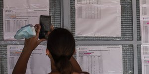 Πανελλήνιες 2021 αποτελέσματα σε πίνακες κοπέλα με κινητό βγάζει φωτογραφία