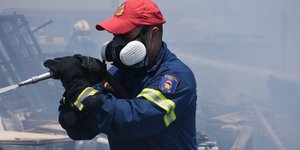 πυροσβέστης με μάνικα κόκκινο καπέλο και μάσκα οξυγόνου