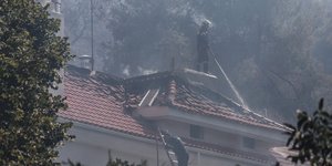 Πυροσβέστης σβήνει τη φωτιά από τη στέγη σπιτιού στη Σταμάτα