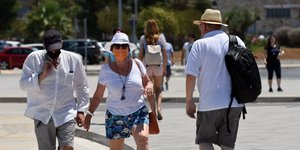 μάσκες με τουρίστες περπατούν στον δρόμο το καλοκαίρι