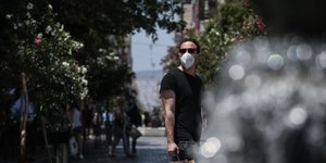 άνδρας με λευκή μάσκα στην Ερμού κοντά σε συντριβάνι