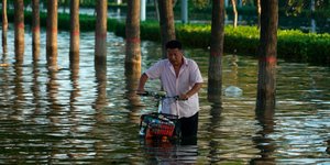 άνδρας με ποδήλατο σε νερά μετά από πλυμμήρες στην Κίνα