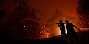 πυροσβέστες ρίχνουν νερό σε φωτιά