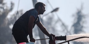 πυροσβέστης με μάνικα ρίχνει νερό σε φωτιά