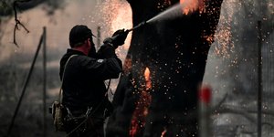 πυροσβέστης με μάνικα ρίχνει νερό σε φωτιά στην Εύβοια