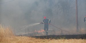 πυροσβέστης σβήνει με μάνικα τη φωτιά στη Βαρυμπόμπη