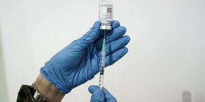 Νοσκόμα με γάντια παίρνει τη δόση του εμβολίου ενάντια στον κορωνοϊό