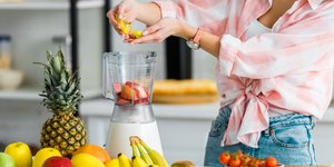 γυναίκα βάζει στο μπλέντερ φρούτα