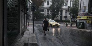 Κακοκαιρία, βροχή στην Αθήνα, άνδρας τρέχει στον δρόμο