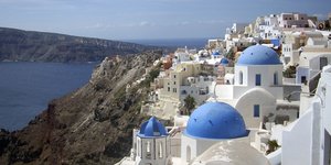 Χαρακτηριστικοί μπλε τρούλοι ναών στη Σαντορίνη με φόντο το γαλάζιο του ουρανού και της θάλασσας