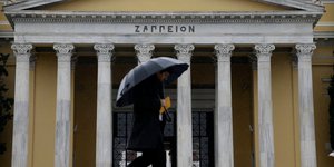 άνδρας με ομπρέλα περνά μπροστά από το Ζάππειο