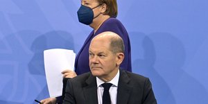 Η Άνγκελα Μέρκελ με μάσκα περνά πίσω από τον Όλαφ Σολτς