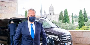 Ο Μάκης Βορίδης περπατά με μάσκα μπροστά από ένα αυτοκίνητο