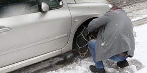 άνδρας βάζει αντιολισθητικές αλυσίδες σε αυτοκίνητο