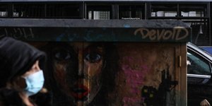 Γυναίκα με μάσκα μπροστά από γκράφιτι στο κέντρο της Αθήνας