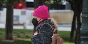γυναίκα με μαύρη μάσκα και φούξια σκούφο περπατά στην Αθήνα