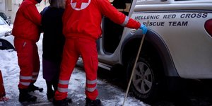 Διασώστες του Ελληνικού Ερυθρού Σταυρού βοηθούν ηλικιωμένη 