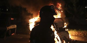αστυνομικός μπροστά σε φωτιά σε διαδήλωση στην Κολομβία
