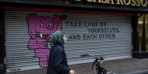 Γυναίκα με μάσκα περπατά μπροστά σε κλειστό κατάστημα Ολλανδία