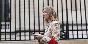 γυναίκα με παλτό και κόκκινη τσάντα περπατά στο δρόμο