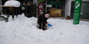 Γυναίκα ξεφτυαρίζει το χιόνι έξω από το μαγαζί της