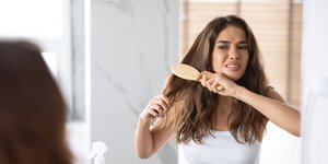 κοπέλα δυσκολεύεται να βουρτσίσει τα μαλλιά της