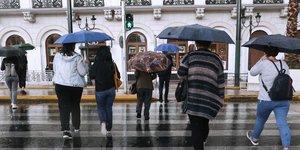 Κόσμος με ομπρέλες περπατά σε διάβαση