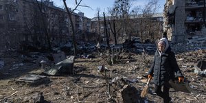 Μια γυναίκα στέκεται ανάμεσα σε συντρίμμια μπροστά από ένα συγκρότημα κατοικιών που υπέστη σοβαρές ζημιές από μια ρωσική επίθεση στις 18 Μαρτίου 2022 στο Κίεβο της Ουκρανίας