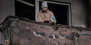 Πολίτης του Κιέβου υψώνει σημαία της Ουκρανίας σε βομβαρσισμένο κτίριο-