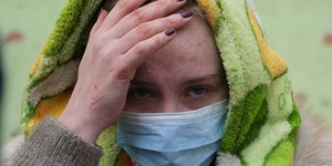 Γυναίκα έξω από το βομβαρδισμένο νοσοκομείο της Μαριούπολης