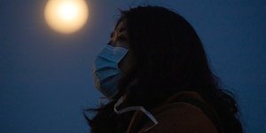 Γυναίκα με μάσκα στην Ουχάν με φόντο το φεγγάρι
