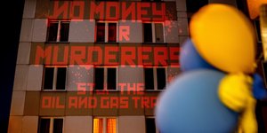 Οι λέξεις «Όχι χρήματα σε δολοφόνους, Σταματήστε το εμπόριο πετρελαίου και αερίου», προβάλλονται από ακτιβιστές στο ρωσικό προξενείο στη Φρανκφούρτη, ζητώντας αυστηρότερες κυρώσεις