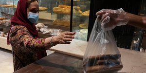 Γυναίκα στο Ιράν αγοράζει ψωμί -Αυξήσεις ως και 300% στα τρόφιμα