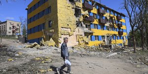 Ένας κάτοικος της Μαριούπολης περπατάει μπροστά από ένα κατεστραμμένο κτίριο