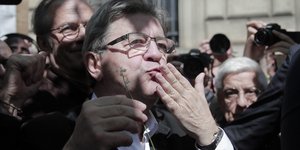 Ο Ζαν-Λυκ Μελανσόν κρατάει ένα κρίνο σε εκδήλωση για την πρωτομαγιά στο Παρίσι