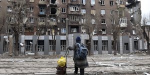 άνθρωπος κοιτά κατεστραμμένο κτίριο στην Ουκρανία