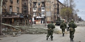 Στρατιώτες της Λαϊκής Δημοκρατίας του Ντονέτσκ περπατούν δίπλα σε κατεστραμμένα κτίρια στη Μαριούπολη