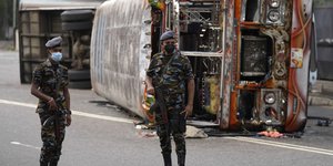 Στρατιώτες περιπολούν στους δρόμους της Σρι Λάνκα, ενώ στο φόντο είναι ακόμη ορατά τα αποτελέσματα των χθεσινών διαδηλώσεων