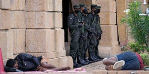 Στρατιώτες στέκονται μπροστά από την είσοδο του προεδρικού γραφείου της Σρι Λάνκα, ενώ διαδηλωτές κοιμούνται στον δρόμο