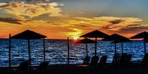 Ξαπλώστρες σε παραλία το ηλιοβασίλεμα