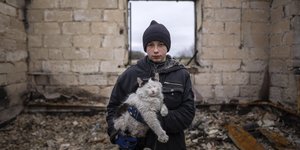 Αγόρι με γάτο στα χέρια εν μέσω ερειπίων στη βομβαρδισμένη Ουκρανία