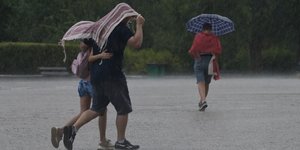 Αθηναίοι προσπαθούν να προστατευτούν από την ισχυρή βροχόπτωση