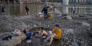 Πολίτες κάθονται δίπλα δίπλα στον ποταμό Τζιανλίνγκ  στην Κίνα κατά τη διάρκεια καύσωνα/ Φωτογραφία: AP