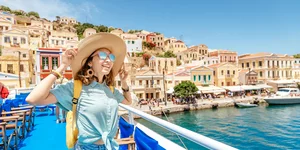 τουρίστρια με σακίδιο και καπέλο απολαμβάνει μια κρουαζιέρα στη θάλασσα σε ένα ανοιχτό κατάστρωμα πλοίου σε ελληνικό προορισμό