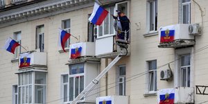 Εργάτες κρεμούν σημαίες της Ρωσίας σε πολυκατοικία στο Λουχάνσκ μετά τα δημοψηφίσματα