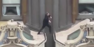 Ο άνδρας με το κοστούμι τρέχει και πηδάει πάνω στην κορυφή του πανύψηλου κτιρίου 