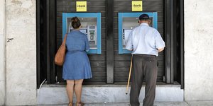 Δυο πολίτες πραγματοποιούν συναλλαγές σε τραπεζικό ΑΤΜ